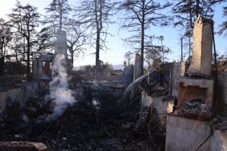 A firefighter hoses down a property destroyed in the Eaton Fire.