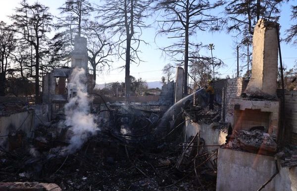 A firefighter hoses down a property destroyed in the Eaton Fire.