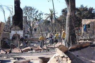 Firefighters sift debris at a property destroyed in the Eaton Fire.