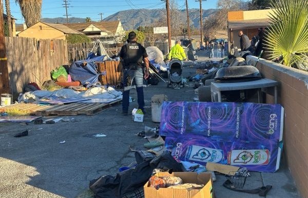 A San Bernardino police officer and city workers remove an encampment Jan. 8 in an alley near Baseline Street.