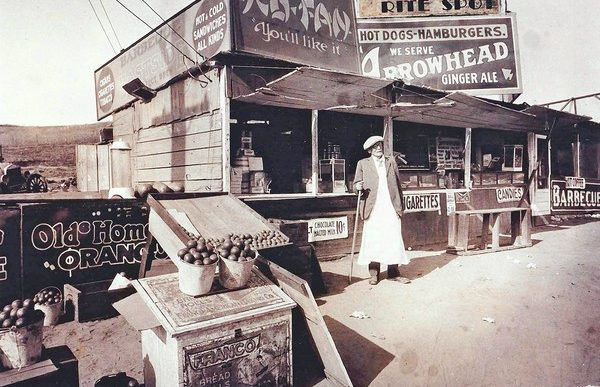 Lionel Sternberger is said to have invented the cheeseburger in the mid-1920s at this roadside snack stand on Colorado Boulevard in Pasadena. Pictured is Lionel's father, Herman Sternberger. The stand was later rebuilt as a restaurant named the Rite Spot. The photograph was displayed in at least one restaurant later operated by the family and appears to have been labeled to reflect the franchise name.