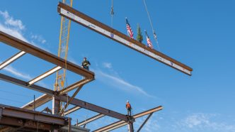 A ceremonial tree flanked by American flags heads toward the top of the Wellness Village construction project in Mead Valley.