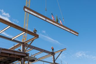 A ceremonial tree flanked by American flags heads toward the top of the Wellness Village construction project in Mead Valley.